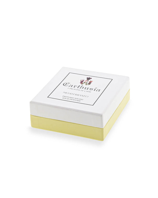 A square box with a white lid and pale yellow base, labeled "Carthusia I Profumi di Capri" and a decorative crest, contains Mediterraneo Solid Perfume scented with sparkling green tea and fresh lemon leaf.