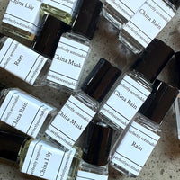 Several Perfectly Scentsable mini rollerball bottles with black caps, including the "China Llily" scent, are labeled and scattered on a surface.