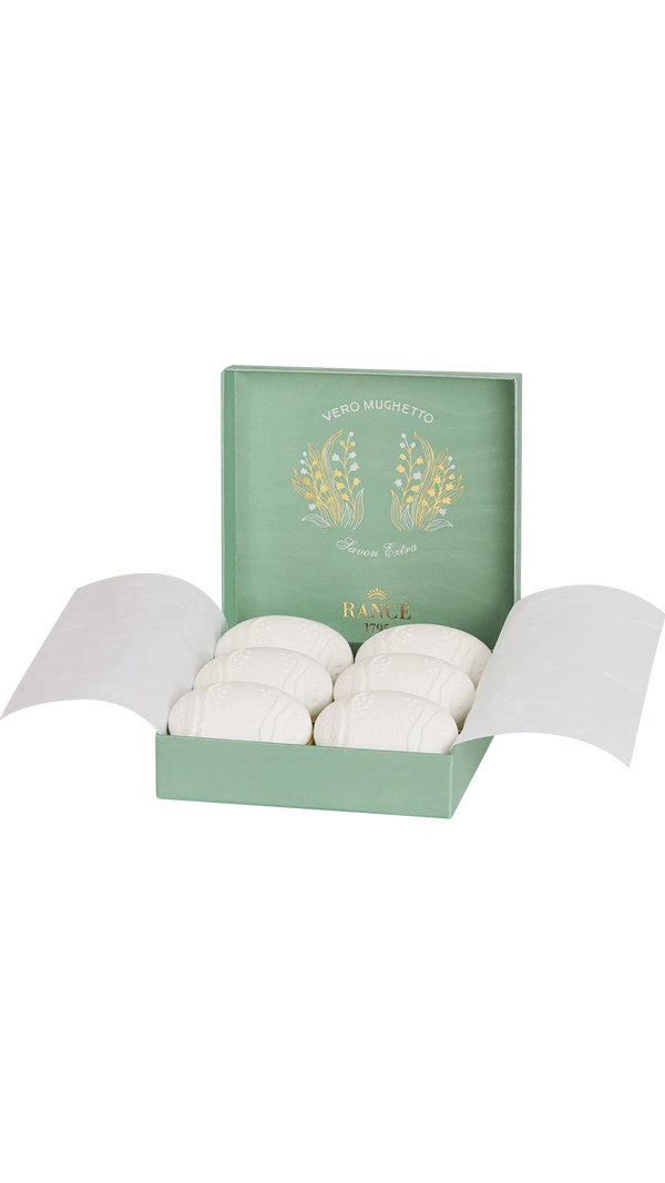 Inside an elegant green box, eight white oval soaps, each in delicate paper, are revealed. The lid displays a floral design with "Vero Mughetto" and "Rancé 1795." These Rancé Classic Soap bars emit a singular Lily of the Valley aroma.