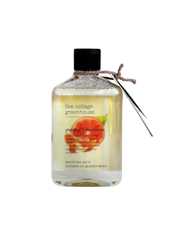 A transparent bottle of Margot Elena's The Cottage Greenhouse Grapefruit & Blood Orange Body Wash, labeled grapefruit and blood orange, with moisture-rich content, tied with a twine at the neck, on a white