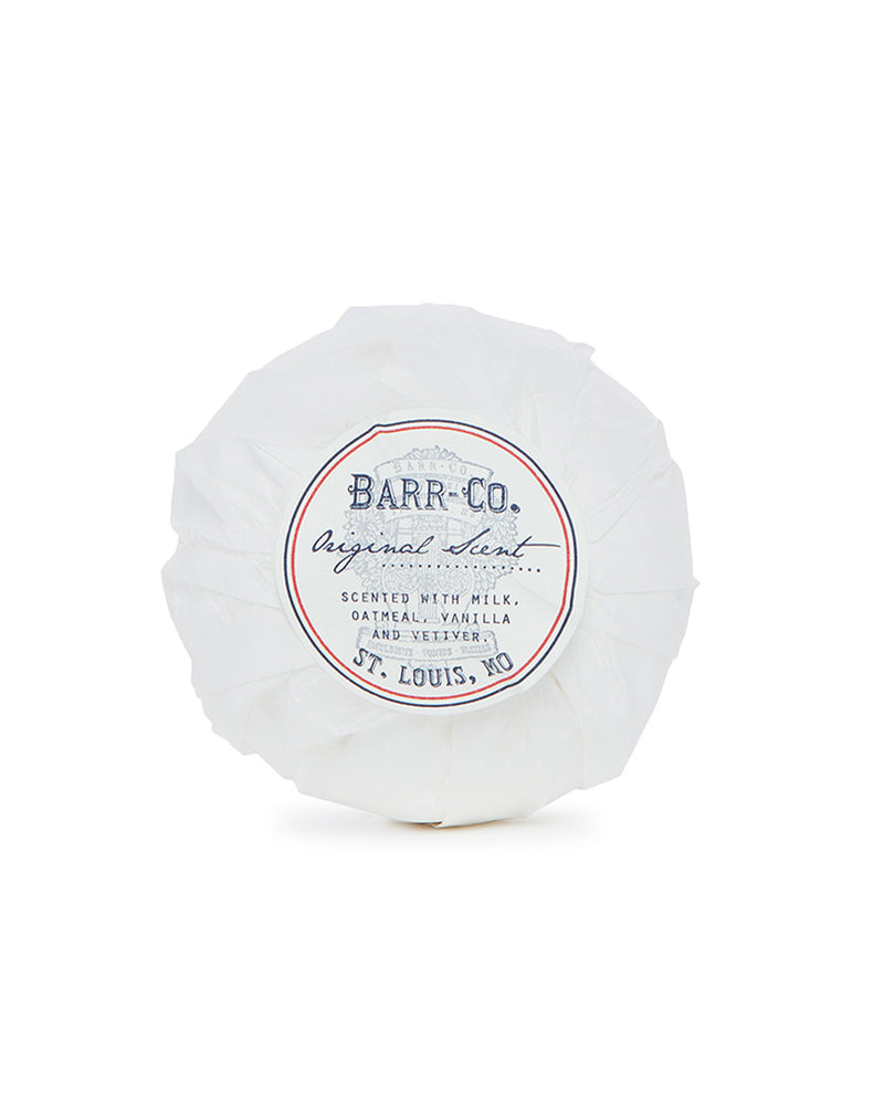 A luxury round bath bomb from Barr-Co., wrapped in white paper featuring "Barr-Co. Original Scent" and "St. Louis, MO," is infused with milk, oatmeal, vanilla, and vetiver aromas.