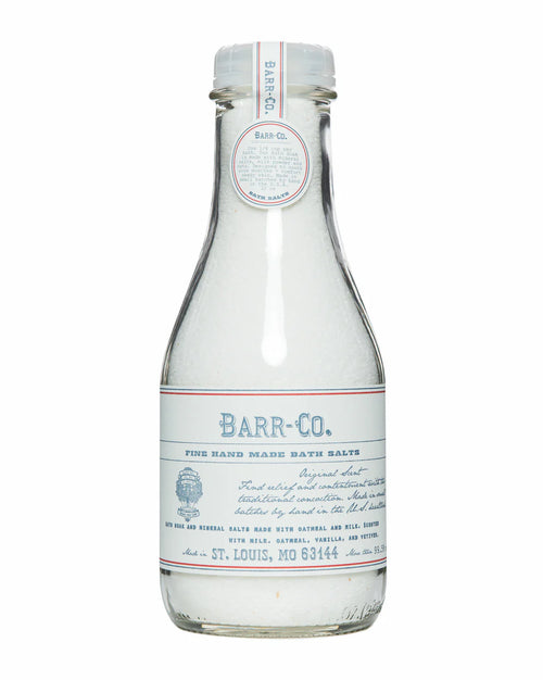 A clear glass bottle with a white and blue label and matching cap, labeled "Barr-Co. Original Scent Bath Soak Salt," contains white mineral bath salts made by Barr-Co. The label features product details and origin information.