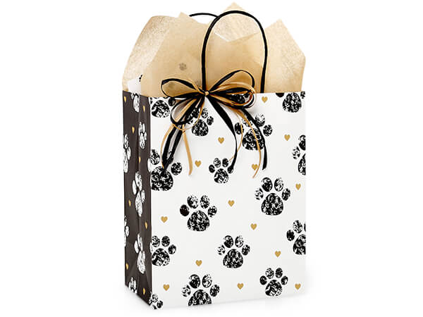 The Nashville Wraps Paws and Hearts Paper Gift Bag 8x4.75x10" features black paw prints and gold hearts, includes beige tissue and a black & gold ribbon—an eco-friendly choice for special occasions.