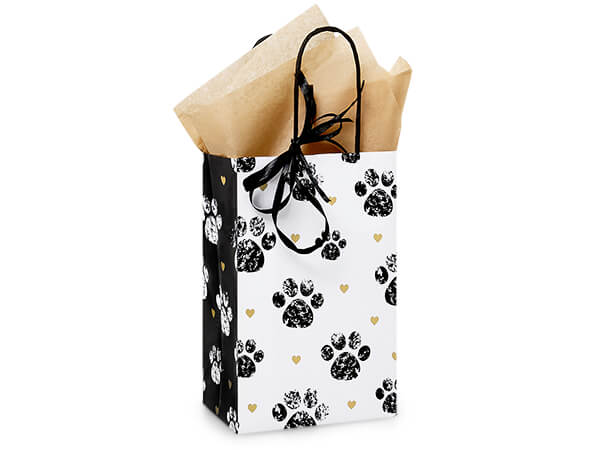 The Nashville Wraps Paws and Hearts Paper Gift Bag (5.25x3.5x8.25") features black paw prints, gold hearts, black ribbon handles, recycled kraft paper construction, and comes filled with brown tissue paper.