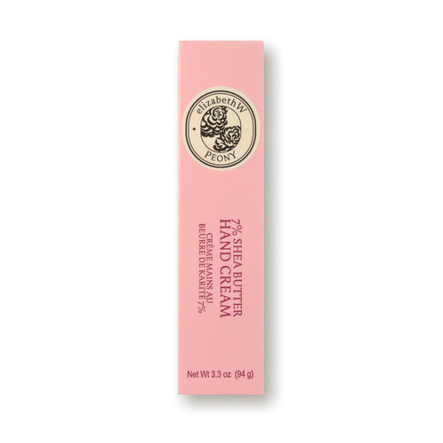 A pink rectangular box of elizabeth W Botanist's Scent Lab Peony Hand Cream features a circular emblem adorned with flowers. The label reads "79% Shea Butter," "Hydrating Hand Cream," "Crème pour les Mains à Beurre de Karité 79%," and "Net Wt 3.3 oz (94 g).