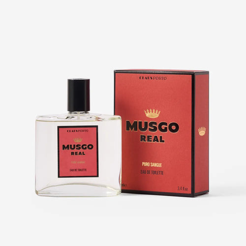 A bottle of Claus Porto Musgo Real Puro Sangue Eau de Toilette by Claus Porto 1887 with a black cap sits beside its matching red and black box, both featuring gold crown logos and bold black lettering inspired by the spirited Lusitano Purebred horse.