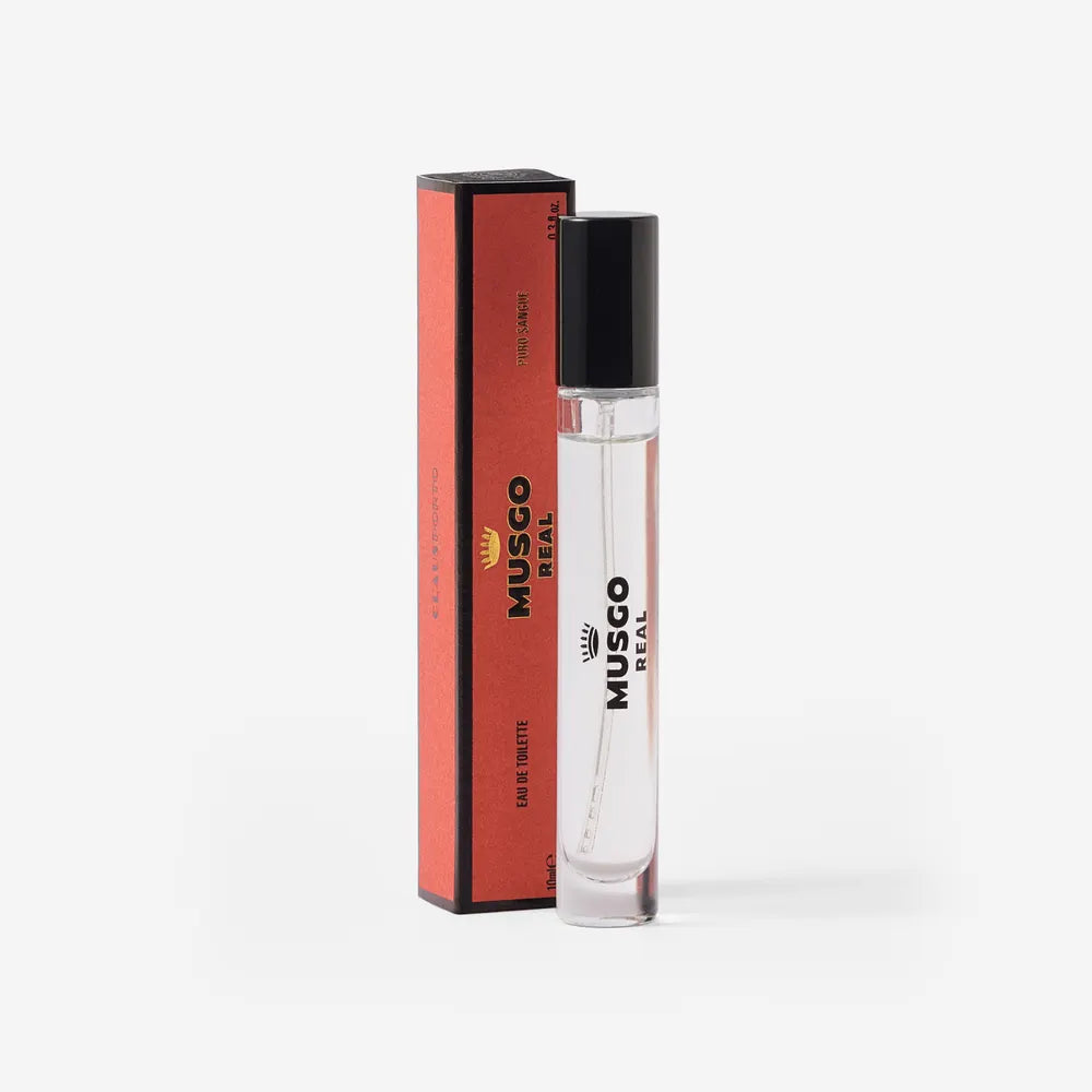 A clear glass bottle of Claus Porto Musgo Real Puro Sangue Eau de Toilette Travel Size by Claus Porto 1887, with a black cap, stands beside its matching red and black box, elegantly displayed on a white background.