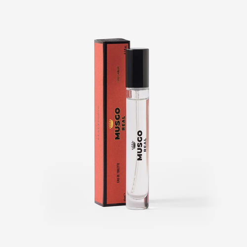 A clear glass bottle of Claus Porto Musgo Real Puro Sangue Eau de Toilette Travel Size by Claus Porto 1887, with a black cap, stands beside its matching red and black box, elegantly displayed on a white background.