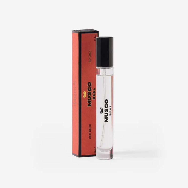A clear glass bottle of Claus Porto Musgo Real Puro Sangue Eau de Toilette Travel Size by Claus Porto 1887, with a black cap, stands beside its matching red and black box, elegantly displayed on a white background.