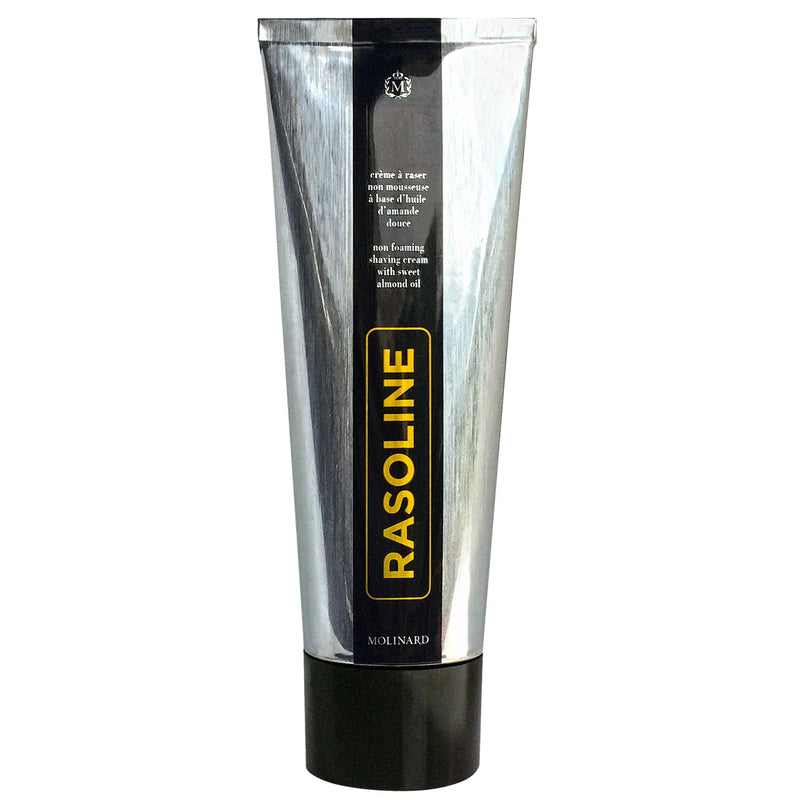 The Molinard Rasoline Shaving Cream comes in a metallic silver tube with "RASOLINE" in bold yellow on a black stripe, "Molinard" at the bottom, and a black screw cap.