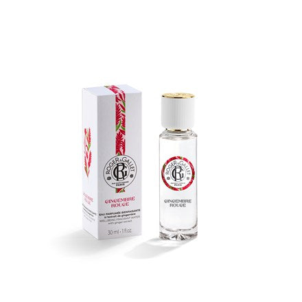 A 1oz Roger & Gallet Red Ginger Wellbeing Water bottle with a gold cap stands next to its white box decorated with red and green leaf designs. The clear glass displays the brand’s label, highlighting this refreshing scent.