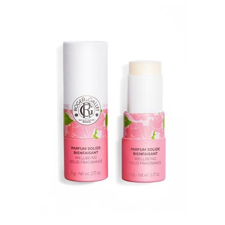 A pink and white Roger & Gallet Rose Wellbeing Solid Perfume stick, cap off to reveal the alcohol-free perfume. The packaging displays floral designs, natural ingredient info, and the Roger & Gallet brand logo.
