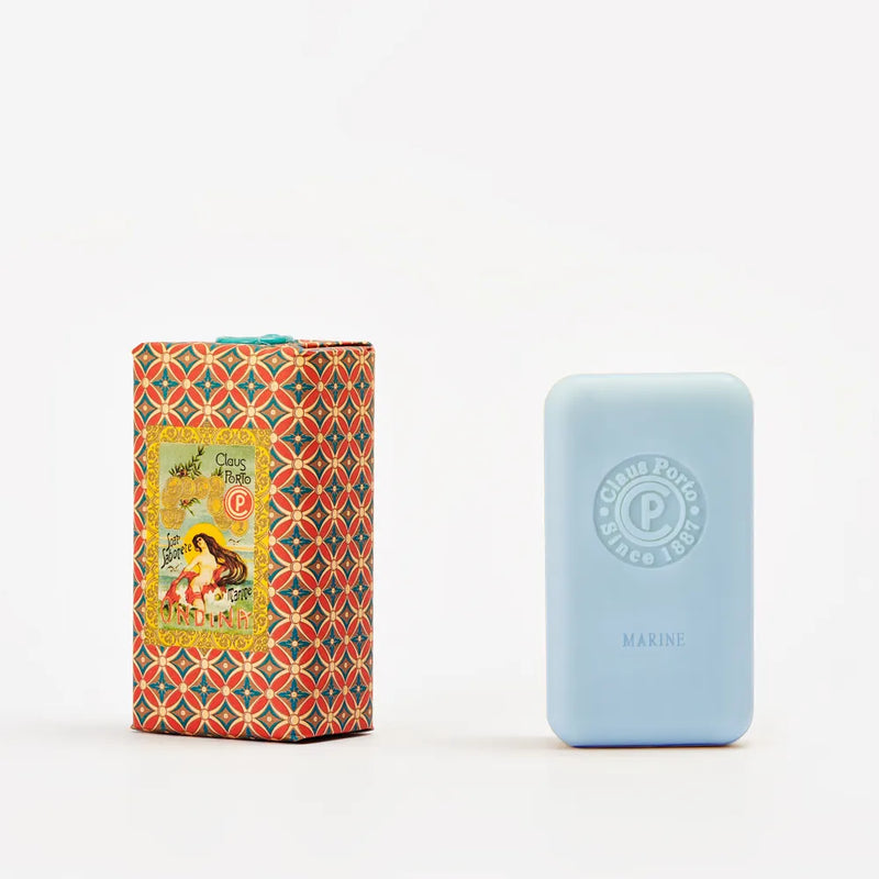 A pale blue rectangular Claus Porto 1887 Classico Odina Sea Mist Soap bar stands next to its ornate, patterned box with a vintage-style label, enriched with nourishing mango seed oil.