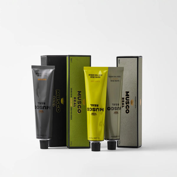 Three tubes of Claus Porto Musgo Real Shaving Cream Essentials by Claus Porto 1887—black, yellow, and olive green—stand upright before their matching boxes, each labeled with the product name and branding on a white background.