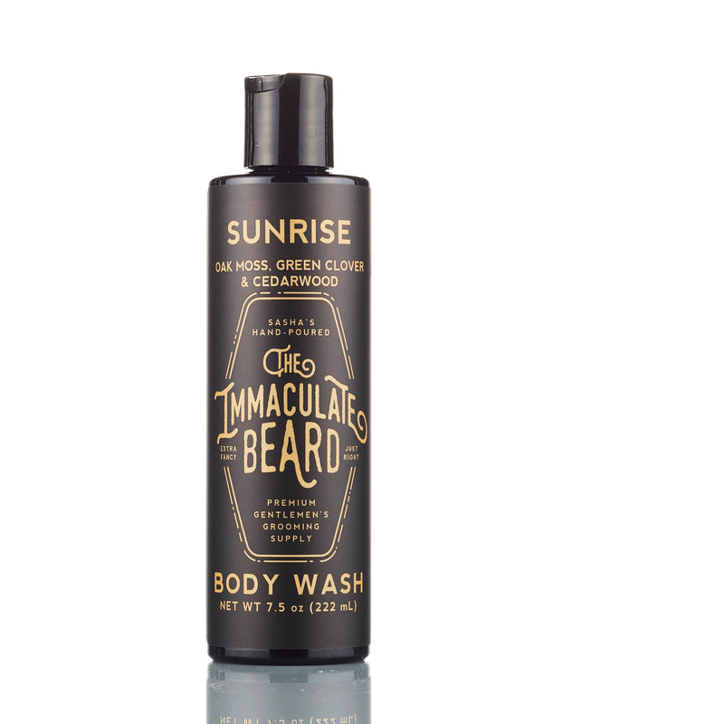 A 7.5 oz (222 ml) black bottle of The Immaculate Beard Sunrise Body Wash is shown against a white background, featuring a natural scent of oak moss, green clover, and cedarwood.