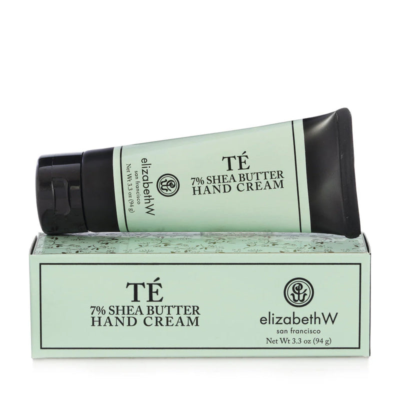 A tube of 7% shea butter hand cream by elizabeth W, lying diagonally on its matching box, against a white background. The packaging is green with elegant floral patterns.
