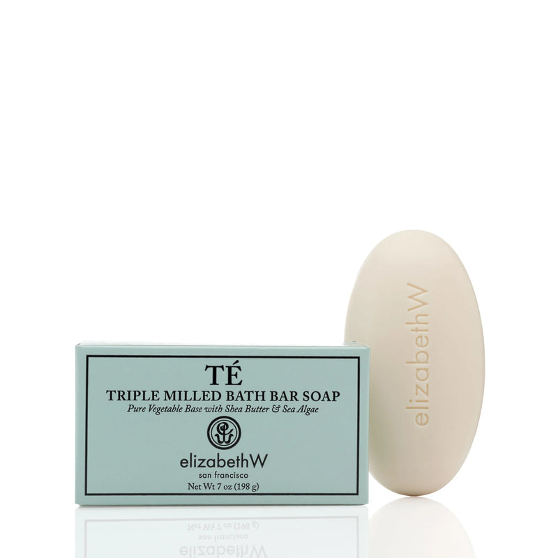 A bar of elizabeth W Signature Té Soap Bath Bar beside its packaging. The packaging is teal with white and black text, and the oval soap has "elizabethw" embossed on it.