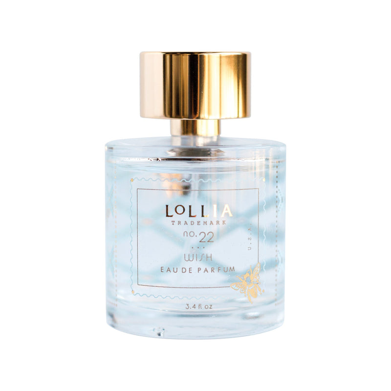 A clear glass perfume bottle labeled "Lolia Wish Parfum Bundle" by Fast Bundle, with gold accents, a shiny gold cap, and containing light blue liquid.