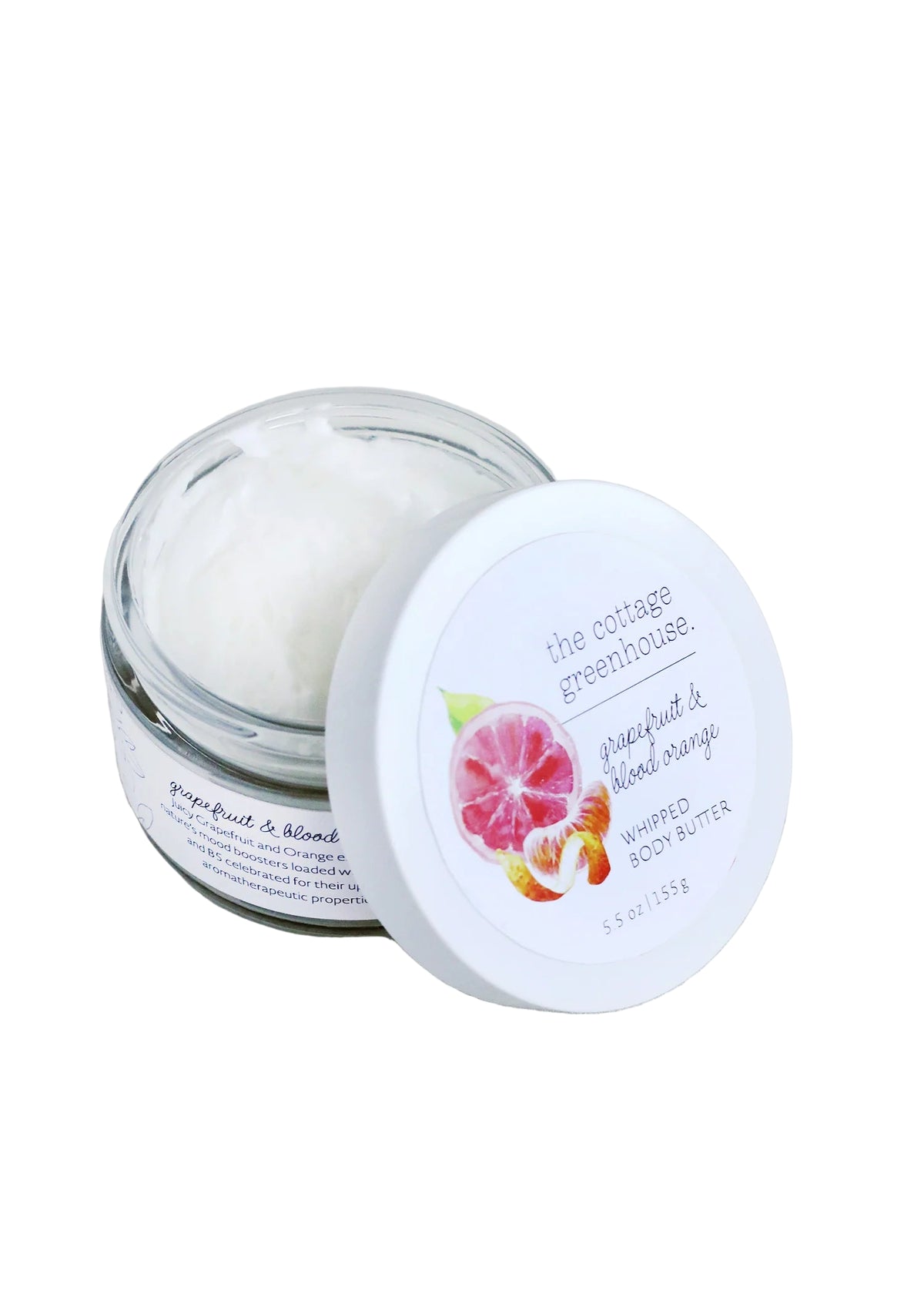 An open glass jar of The Cottage Greenhouse Grapefruit & Blood Orange Body Butter by Margot Elena shows creamy white body butter inside, with the lid featuring an image of grapefruit and blood orange.