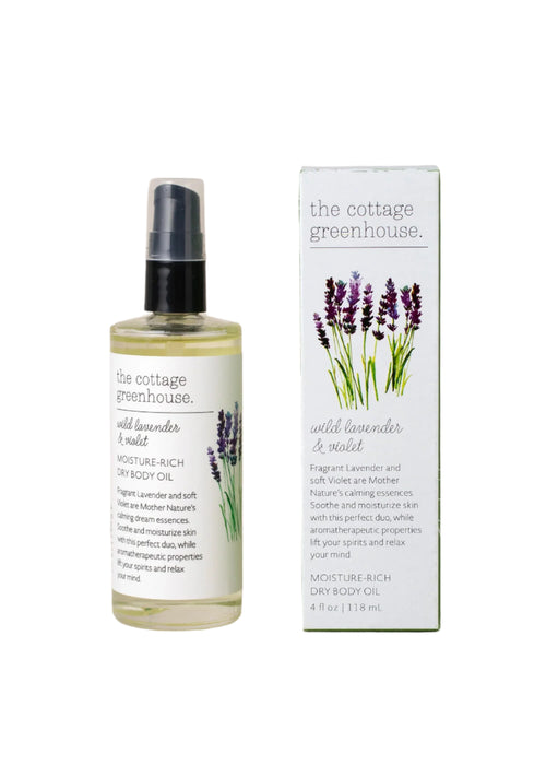 The 4 fl oz (118 mL) "The Cottage Greenhouse Wild Lavender & Violet Dry Oil Body Spray" from Margot Elena features a moisturizing formula, packaged alongside a matching box with lavender sprig illustrations, offering a soothing natural touch.
