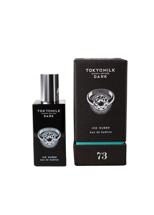 A bottle of Margot Elena's TokyoMilk Dark Ice Queen No. 73 Eau de Parfum beside its box. The packaging features a black backdrop with a skull and crossbones design and turquoise accents.