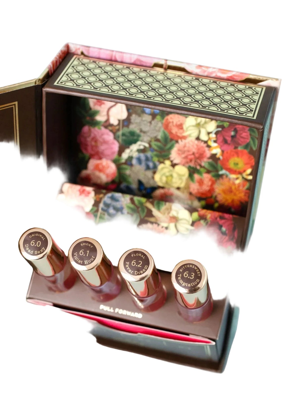 A floral-patterned box with an open lid reveals TokyoMilk Dead Sexy Alchemy Kit by Margot Elena. Four labeled lipsticks (6.0–6.3) stand in a “PULL FORWARD” holder, inviting creative fragrance layering inspired by signature artistry.