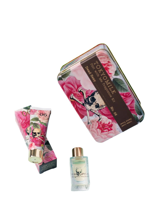 The TokyoMilk Dead Sexy Flirt With Me Kit by Margot Elena features a metallic tin with pink flowers and a skull logo, including a cream tube and liquid bottle, both with matching designs emphasizing the unique Dead Sexy fragrance notes.