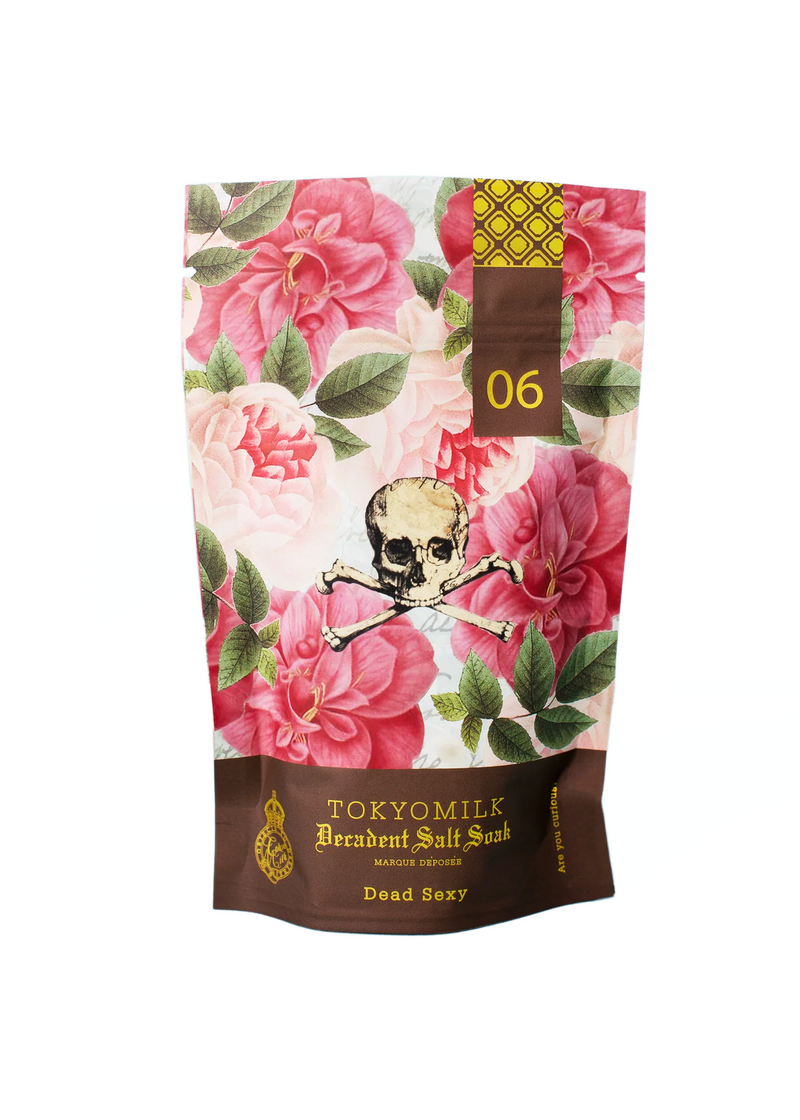 A luxurious Margot Elena TokyoMilk Dead Sexy Salt Soak sachet featuring a floral pattern with pink flowers and a contrasting skull in the center, placed against a white background.