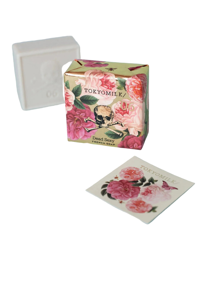 A Margot Elena TokyoMilk Dead Sexy Square Soap, triple-milled and embossed with a skull, is floral-wrapped and paired with a matching card, both elegantly displayed on a white background.