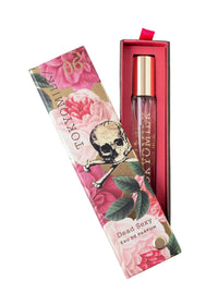A floral-patterned box labeled "TokyoMilk Dead Sexy Travel Spray" by Margot Elena, featuring a skull and crossbones design, is partially open to show a glass perfume bottle with a gold cap inside.