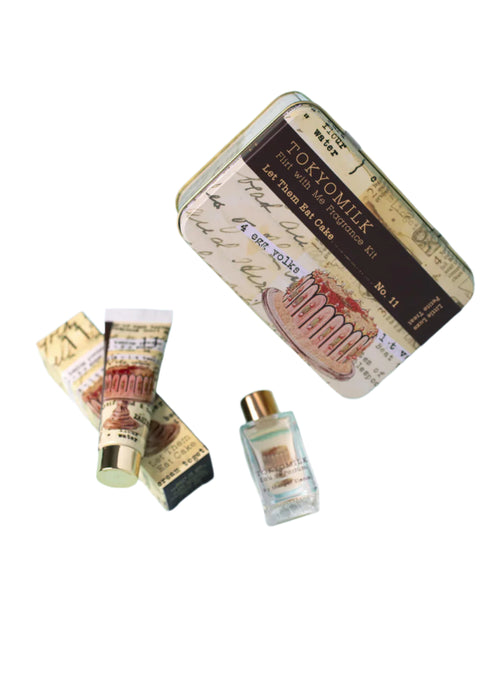The "TokyoMilk Let Them Eat Cake Flirt With Me Kit" by Margot Elena includes a tin box featuring vintage-style text and illustrations, containing a small tube and bottle with nostalgic cursive writing and imagery, suggesting it's a cosmetic or personal care kit.