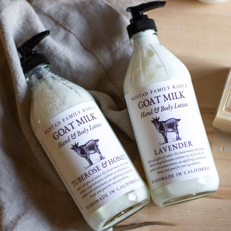 Two bottles of Nustad Family Ranch Tuberose & Honey goat milk hand & body lotion, labeled "tuberose & honey" and "lavender," placed on a beige cloth with a rustic background. Each contains 16oz.
