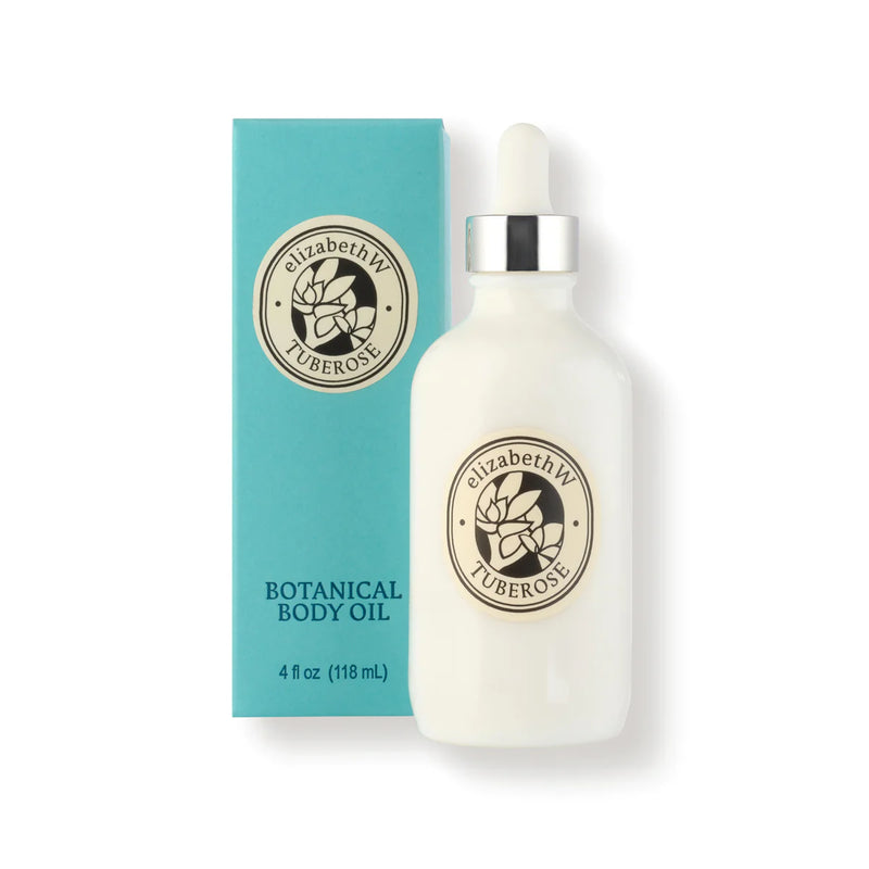 A white bottle with a dropper labeled "elizabeth W Botanist's Scent Lab Tuberose Body Oil" stands beside its matching teal box, exuding a luxurious fragrance. Both feature a circular floral logo and are infused with jojoba and sweet almond oil. The bottle contains 4 fl oz (118 ml) of indulgence.