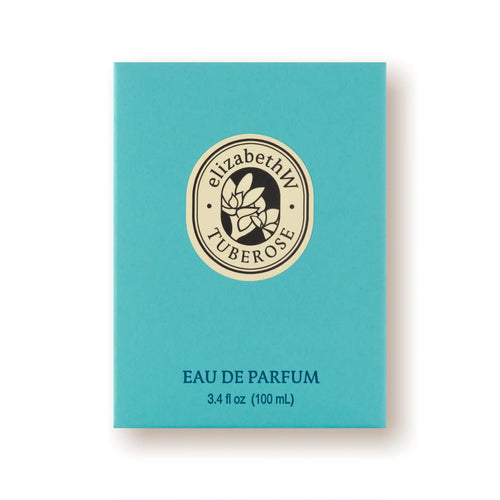 A teal-colored box adorned with a circular beige emblem showcasing a flower and the text "elizabeth W Botanist's Scent Lab Tuberose." Below it, the text reads "EAU DE PARFUM, 3.4 fl oz (100 mL)," suggesting the luxurious fragrance contained within.