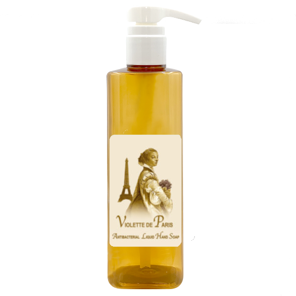 A clear bottle of La Bouquetiere Violette de Paris Liquid Hand Soap with a pump dispenser, filled with yellow liquid. The label features an image of a woman and the Eiffel Tower, and reads "Violette de Paris".