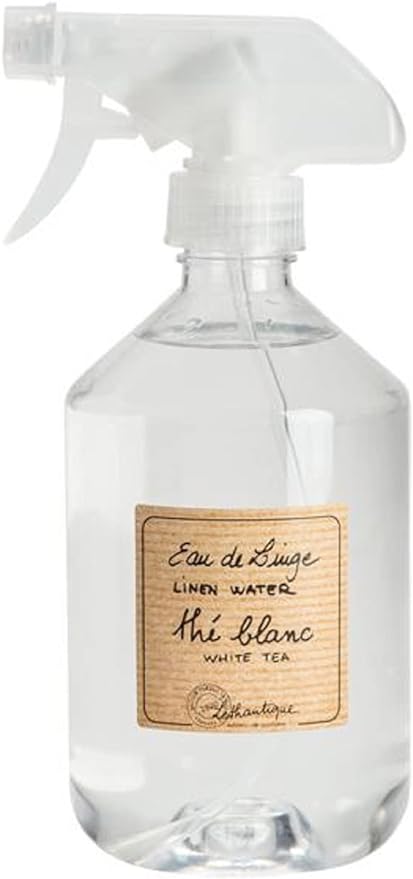 A clear plastic spray bottle labeled "Lothantique White Tea Linen Water" with a sophisticated handwritten font on a beige label. The sprayer is white and translucent.