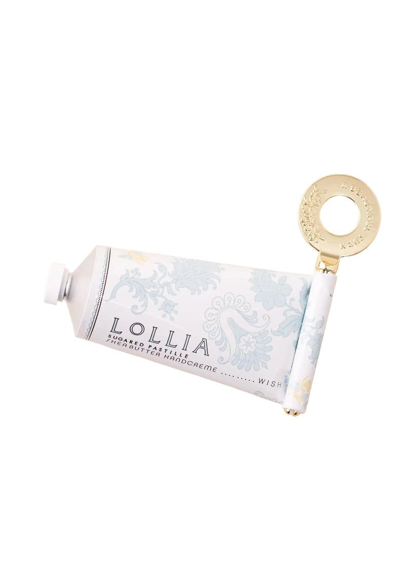 The Lollia "WUTHERING HEIGHTS" Wish Handcreme & Key by Margot Elena features a light blue floral tube, white cap, gold metal key, and is enriched with shea butter for luxurious botanical hand care.