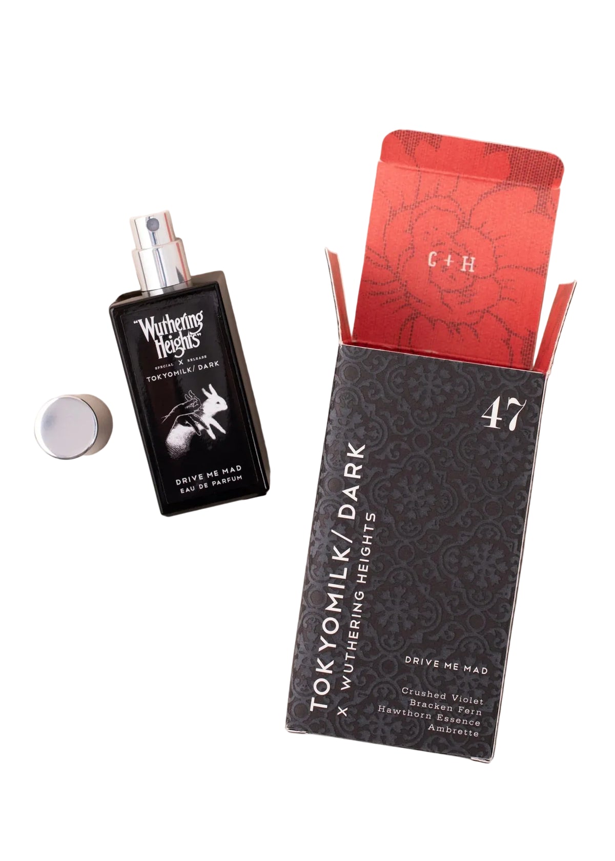 A black bottle of Margot Elena’s TokyoMilk Dark "WUTHERING HEIGHTS" Drive Me Mad Eau de Parfum sits beside its open patterned box, revealing a floral interior and the initials "C+H." Its silver cap is off, suggesting a moody scent within.
