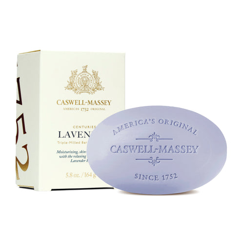 A lavender-colored bar of Caswell Massey Centuries Lavender Bar Soap, triple-milled with embossed logo beside its white packaging box, which features gold accents and text describing the product as a moisturizing bath soap.