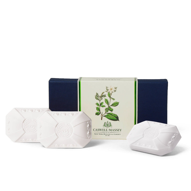 Three Caswell - Massey Gardenia soaps in front of their open navy blue box and a botanical illustration on the packaging.