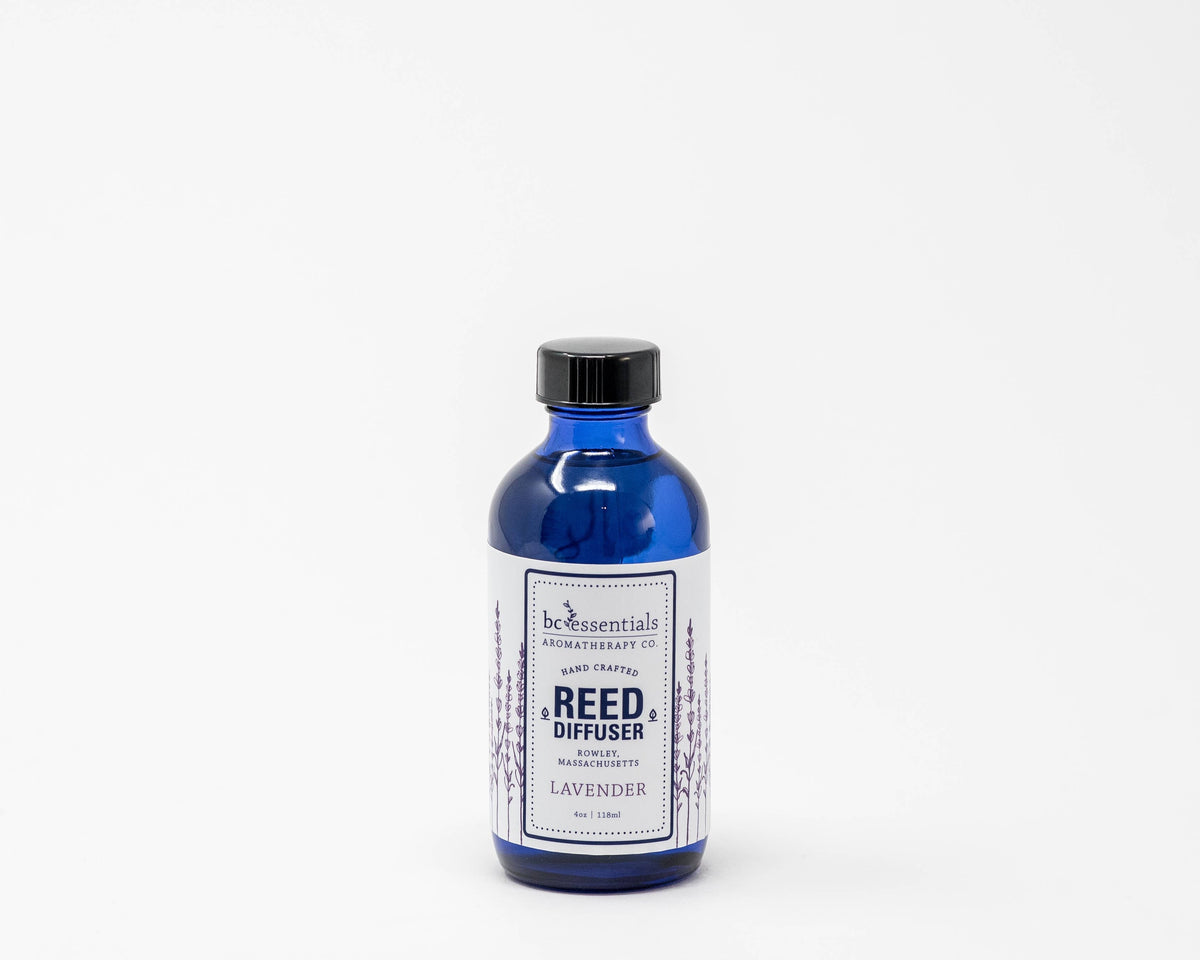 A blue glass bottle of BC Essentials Lavender Reed Diffuser - 4oz against a plain white background. The label is detailed and depicts lavender plants.