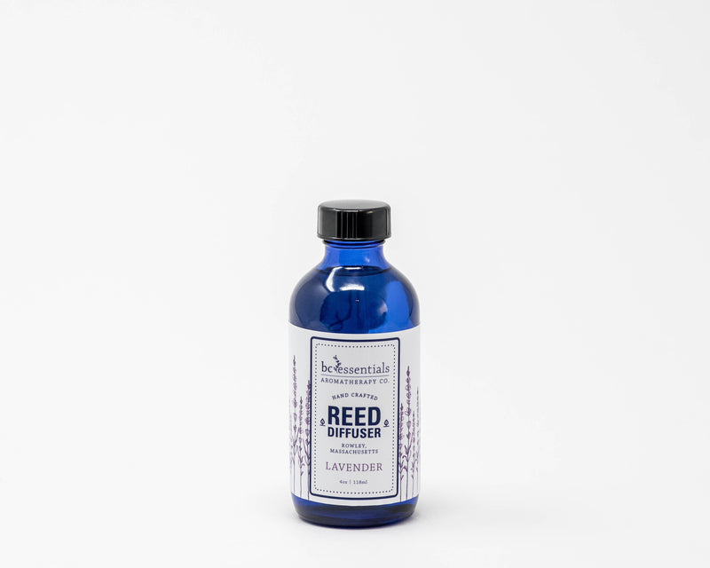 A blue glass bottle of BC Essentials Lavender Reed Diffuser - 4oz against a plain white background. The label is detailed and depicts lavender plants.