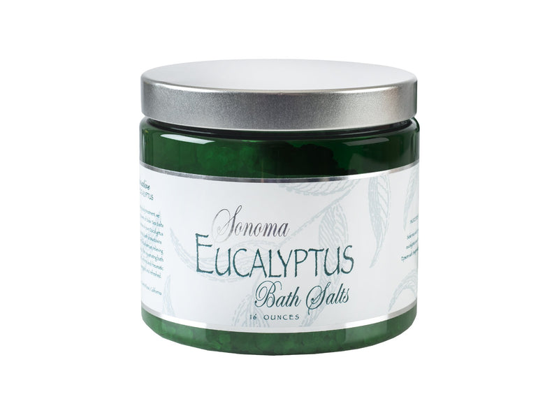 A clear glass jar of Sonoma Lavender eucalyptus bath salts with a silver lid and a label featuring green leaves. The jar contains 16 ounces of detoxifying sea salts.