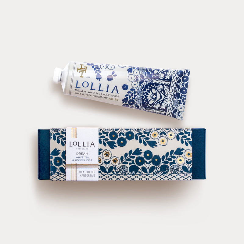 A Margot Elena Lollia Dream Shea Butter Hand Creme tube with a blue and white floral design and a dreamy fragrance of White Tea & Honeysuckle, next to its matching packaging box, set against a white background