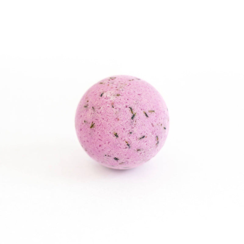 A SOAK Bath Co. Lavender Bath Bomb with specks of black and green, placed centrally on a plain white background.