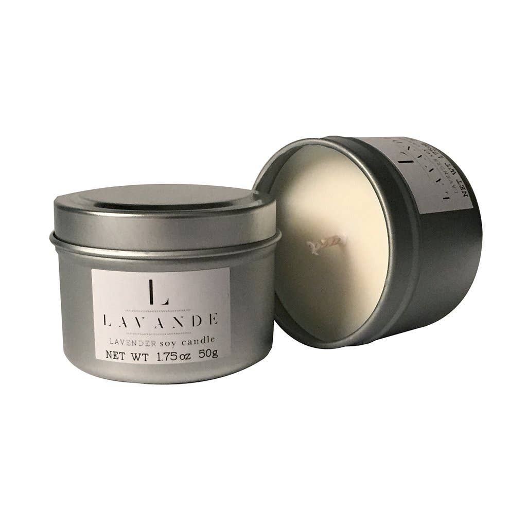 A Lavande Lavender Travel Candle in a small, round, gray tin with the lid slightly off, showing the white candle wax. The label reads "lavande, lavender soy candle, net wt 1