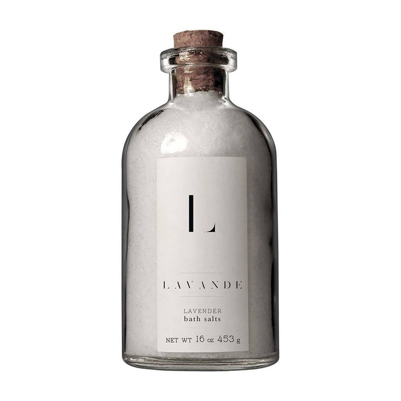 An elegant glass bottle with a cork stopper filled with Lavande - Lavender Bath Salts, labeled "Lavande" with minimalist black and white design, isolated on a white background.