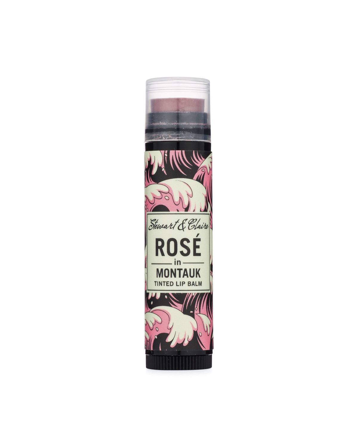A cylindrical lip balm container with a stylish design featuring black zebra stripes and pink accents, labeled "Rosé In Montauk tinted lip balm by Stewart & Claire," enriched with organic virgin coconut.