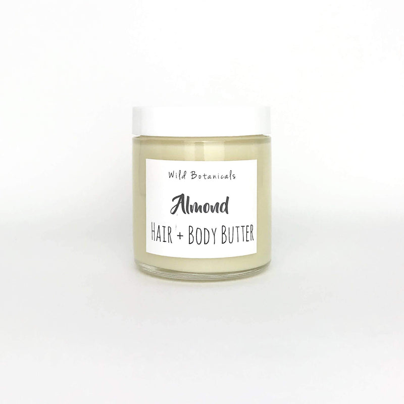 A clear glass jar of Wild Botanicals - Almond Hair and Body Butter with white label on a plain white background, formulated with organic shea butter.