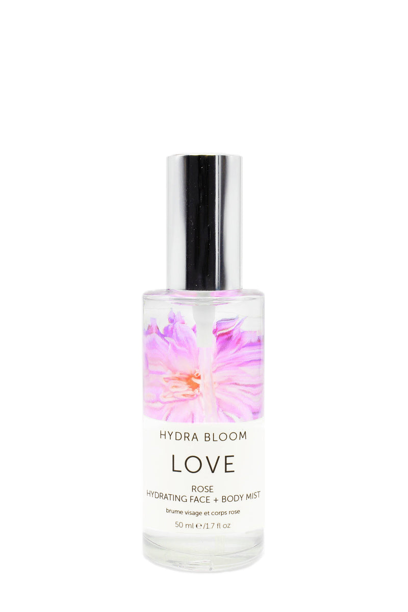 A clear bottle of "Hydra Bloom Beauty Rose Love Face and Body Mist" against a white background, decorated with a pink and purple floral design. The bottle contains 50 ml of the product infused with Hydra Bloom Beauty.